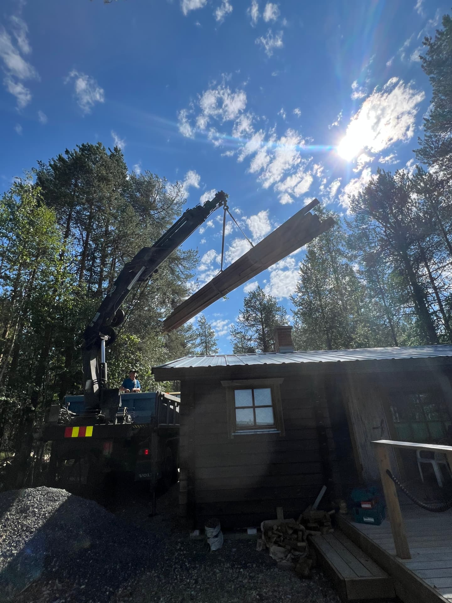 Nosturi nostaa puutavaraa mökin katolle